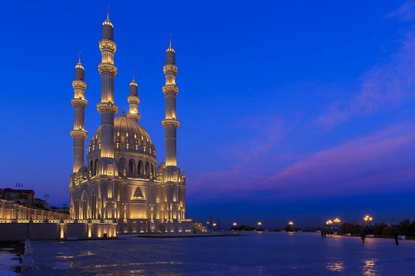 En stor moské med flere kupler og minareter, belyst i skumringen. 4