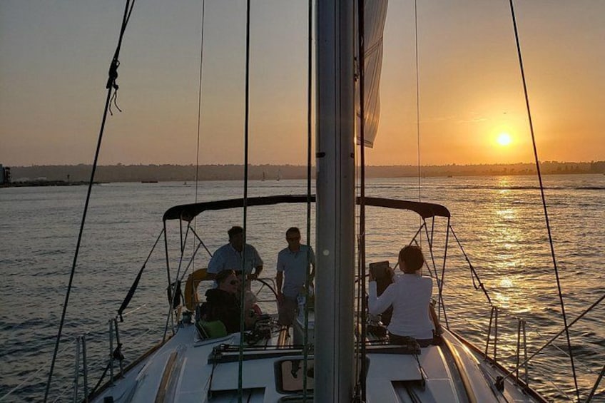 Un velero con gente a bordo, un atardecer de fondo y aguas tranquilas. 5