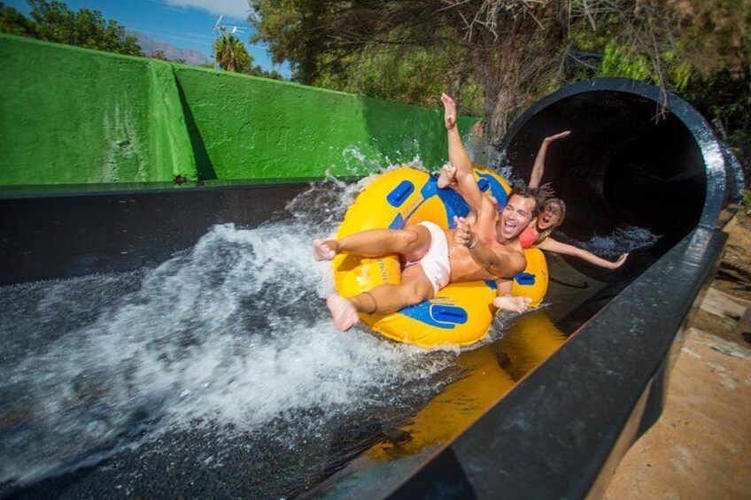 A water slide with a person and a child in a yellow raft. 4