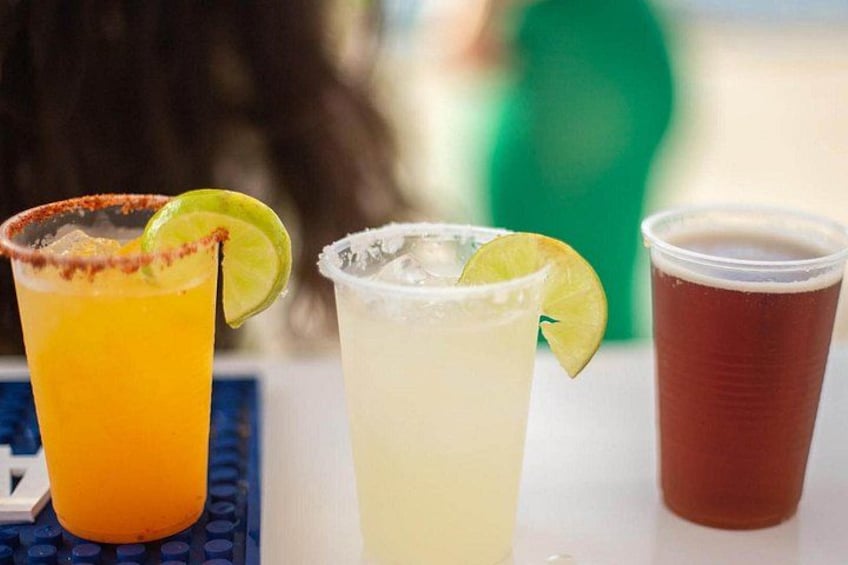 Three glasses of beverages with lime garnishes on a table. 4