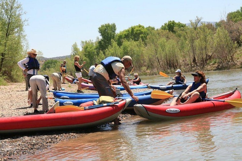 People preparing kayaks on a riverbank. 5