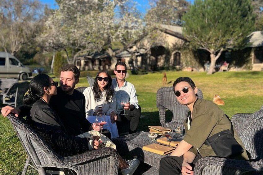 Un grupo de personas sentadas en muebles de mimbre al aire libre, con un edificio y árboles de fondo. 5