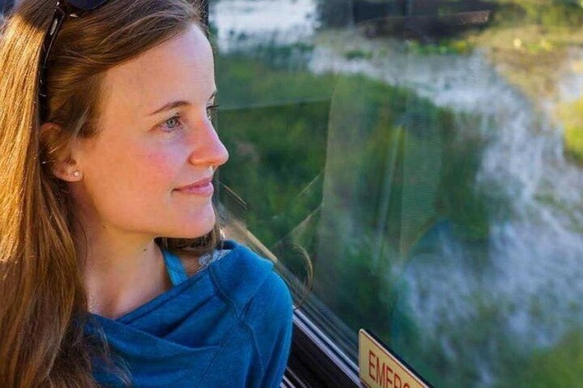 Una persona sentada junto a una ventana con vistas a un cuerpo de agua y follaje. 5