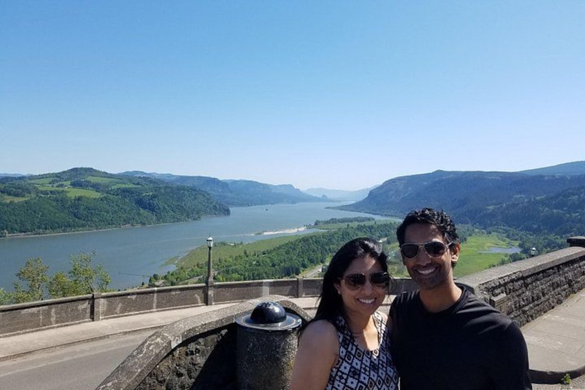 A couple standing on a bridge overlooking a river and hills. 5