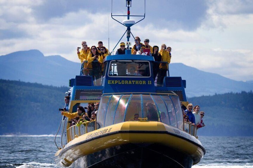 A boat named 'EXPLORATOR II' with people on deck and a mountainous landscape in the background. 5