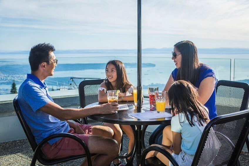 A family of four at a table with drinks, overlooking a scenic view. 2