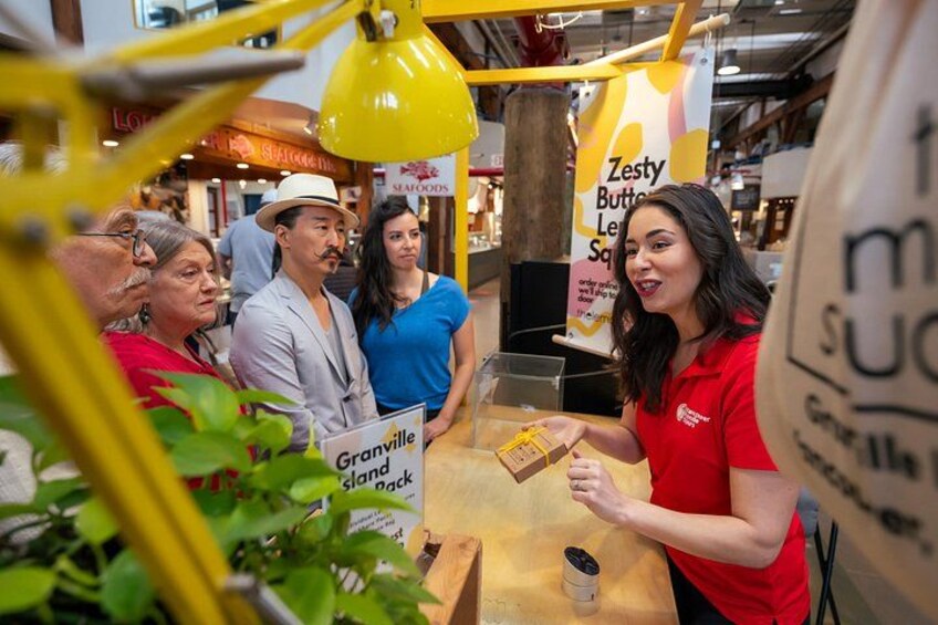 A person in a red shirt at a store counter with a sign that reads 'Granville Island Pack.' 2