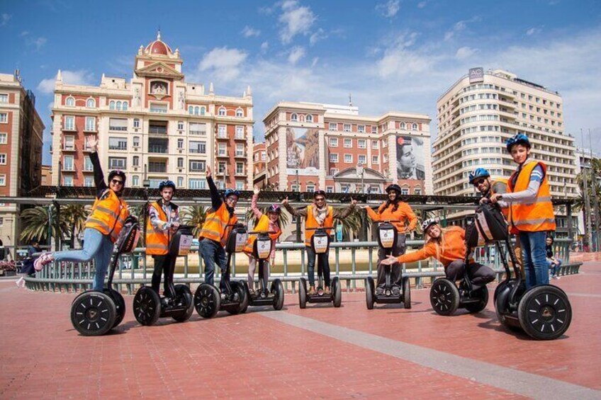 Des personnes se promènent à bord de Segways sur une place publique, avec des bâtiments en arrière-plan. 1