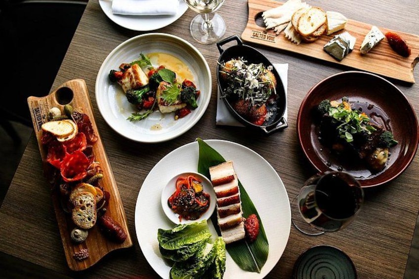 Una mesa de madera con diversos platos, entre ellos un plato con bistec, un bol de sopa y una fuente con verduras. 2