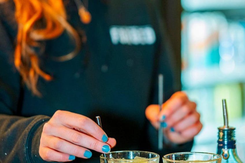 Eine Person mit blauer Nagellack bereitet Getränke mit einem Shaker und einer Flasche zu. 5