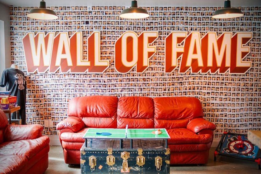Ein rotes Sofa, ein Trupp in Grün und Schwarz sowie eine Wand mit einem 'Wall of Fame'-Schild. 4