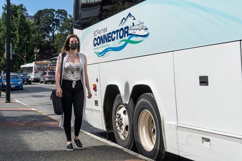 Una mujer caminando al lado de un autobús con un logotipo que dice 'BC Ferries CONNECTOR'. 2