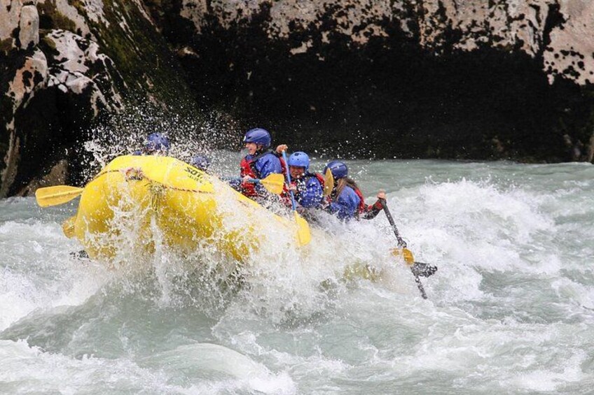 A group of people in a yellow raft navigating through a river with white water rapids. 3