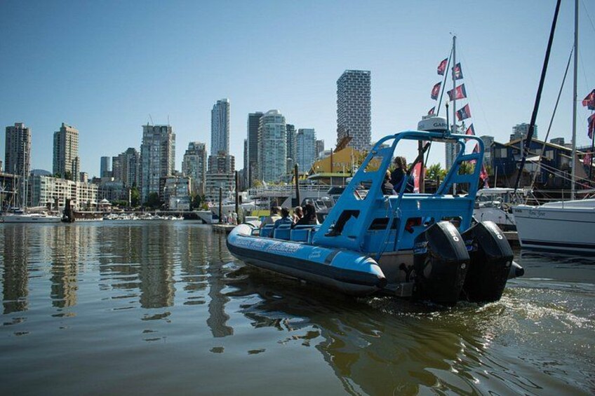 A blue boat with a flag on a calm water body with a city skyline in the background. 2