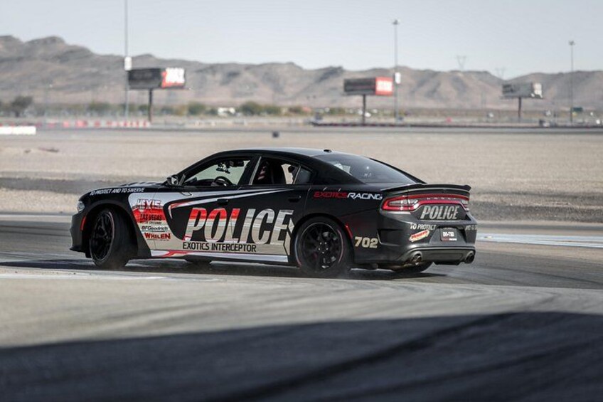 A police car with 'POLICE' and 'EXOTICS INTERCEPTOR' decals on a racetrack. 3