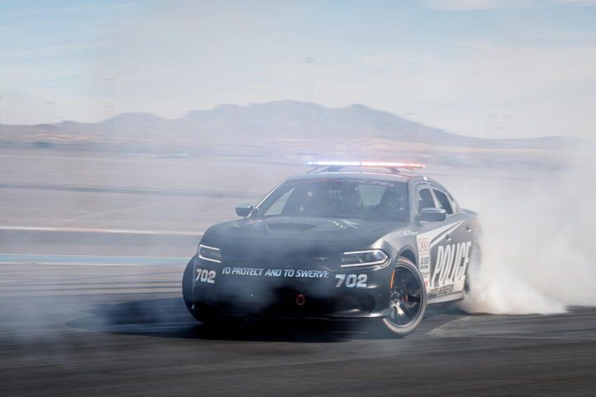 A police car with the number 702 drifting on a track. 2
