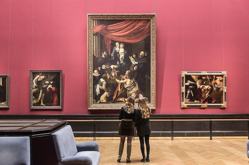 L’intérieur d’un musée avec des murs rouges, de grands tableaux de style classique et un plancher en bois. 3