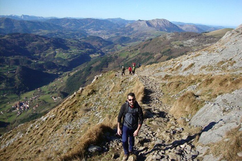 A hiker on a rocky mountain path with a valley in the background. 1