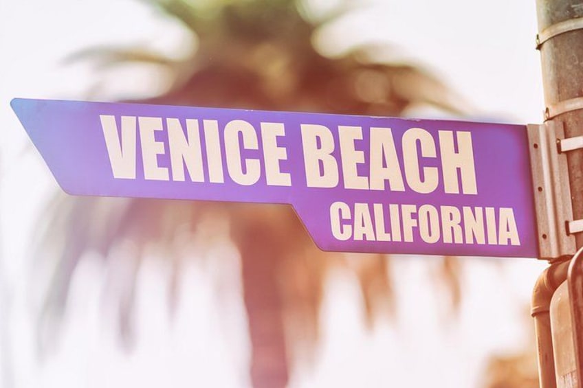 Una señal de calle morada con letras blancas que dice 'Venice Beach California'. 3