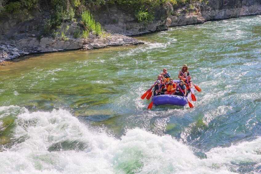 A group of people rafting on a river surrounded by rocky cliffs. 3