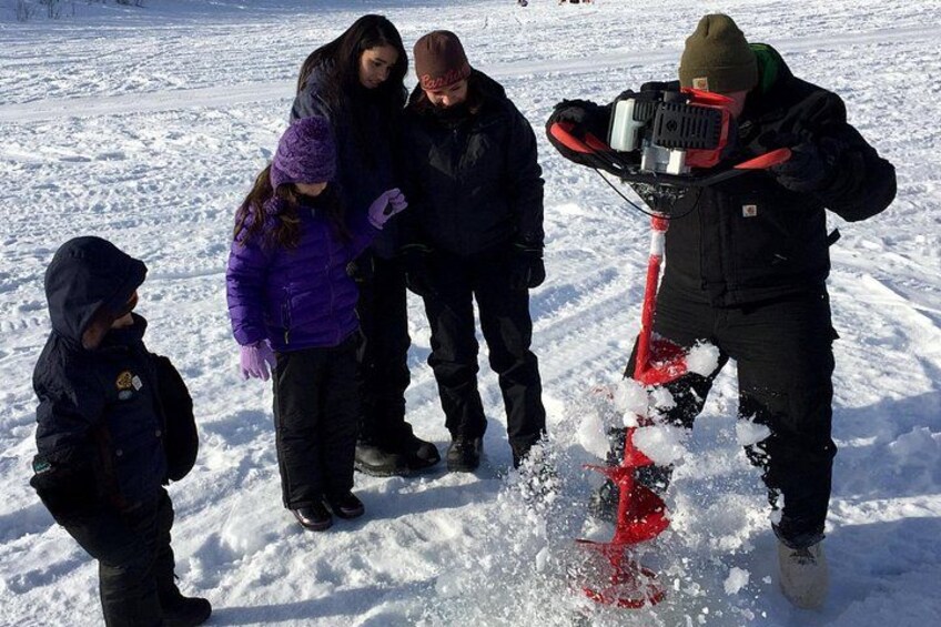 A group of people on a snowy field with a person using a snowmobile. 3