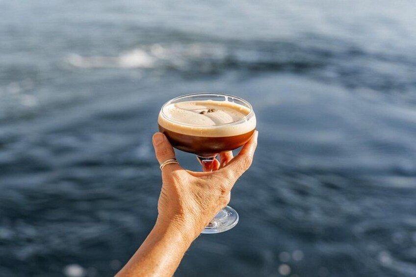 Una mano sosteniendo una taza de café, con vista al océano. 1