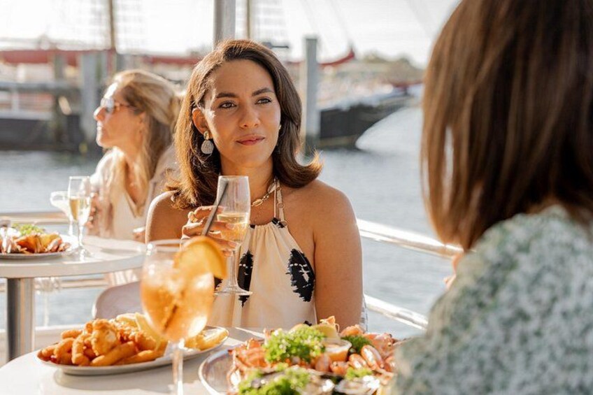 A dining table with food and drinks, a waterfront view, and a bridge in the background. 1