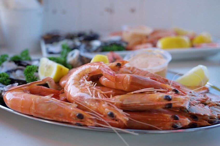 Un plato de camarones cocidos con gajos de limón y un recipiente pequeño de salsa. 4