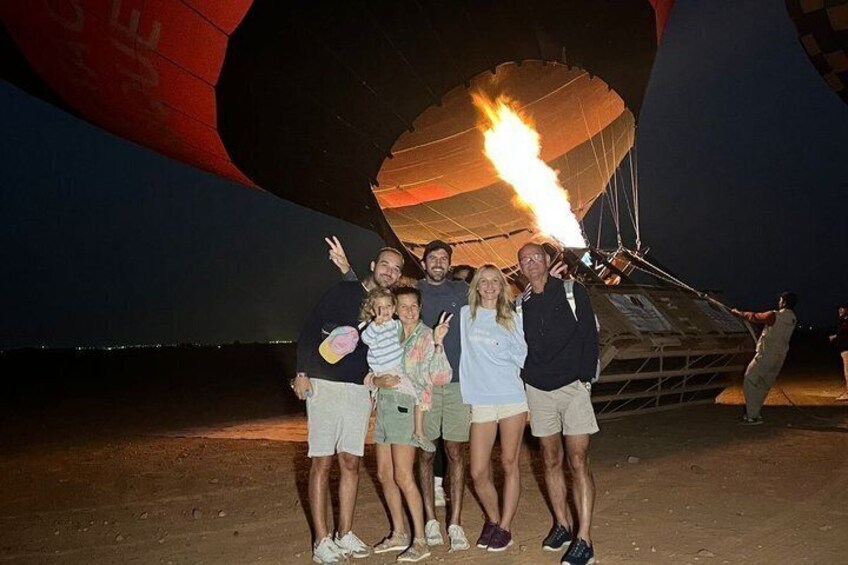 Un groupe de personnes posant devant une montgolfière dont on peut voir les flammes. 2