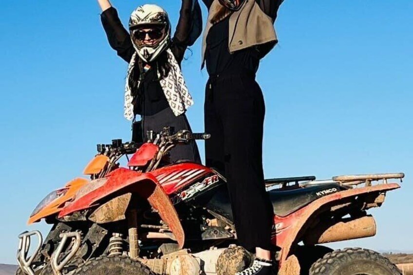 Une personne se tient debout sur un quad rouge, portant un casque et une écharpe, et une autre personne se trouve à côté d’elle. 5
