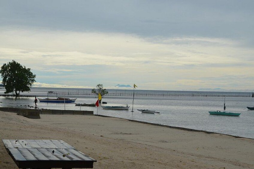 A beach with boats, a pier, and a cloudy sky. 2