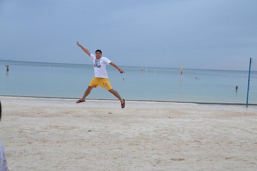 A person playing beach volleyball on a sandy beach with the ocean in the background. 4