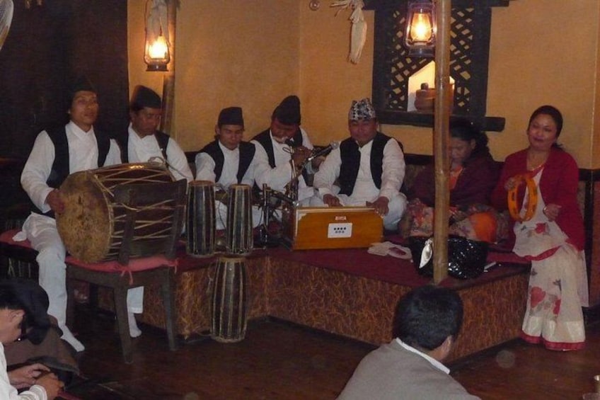 Un grupo de músicos interpretando con instrumentos tradicionales en una habitación tenuemente iluminada. 3