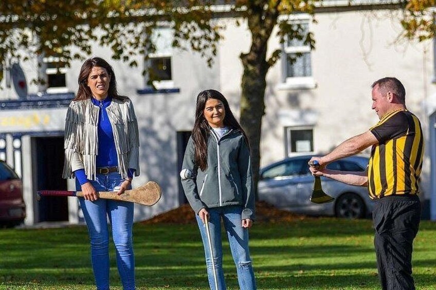 Drei Personen auf einer Wiese, im Hintergrund ein Gebäude. 3