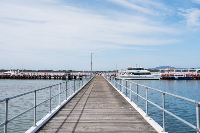 A wooden pier extending into calm water with boats docked on both sides. 5