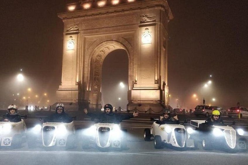 Vista nocturna del Arco del Triunfo con una fila de vehículos en primer plano. 2