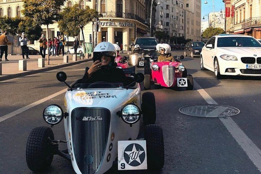 Coches antiguos en una calle de la ciudad, un coche blanco con parrilla negra y un coche rosa con techo blanco. 5