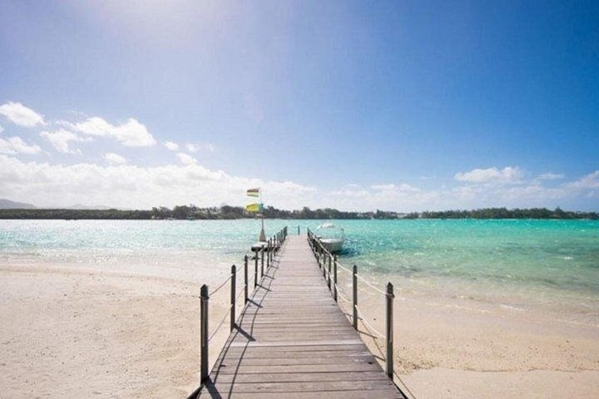 A wooden pier leading to a beach with clear turquoise water. 4
