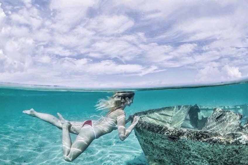 A person swimming near a shipwreck in clear turquoise water. 2
