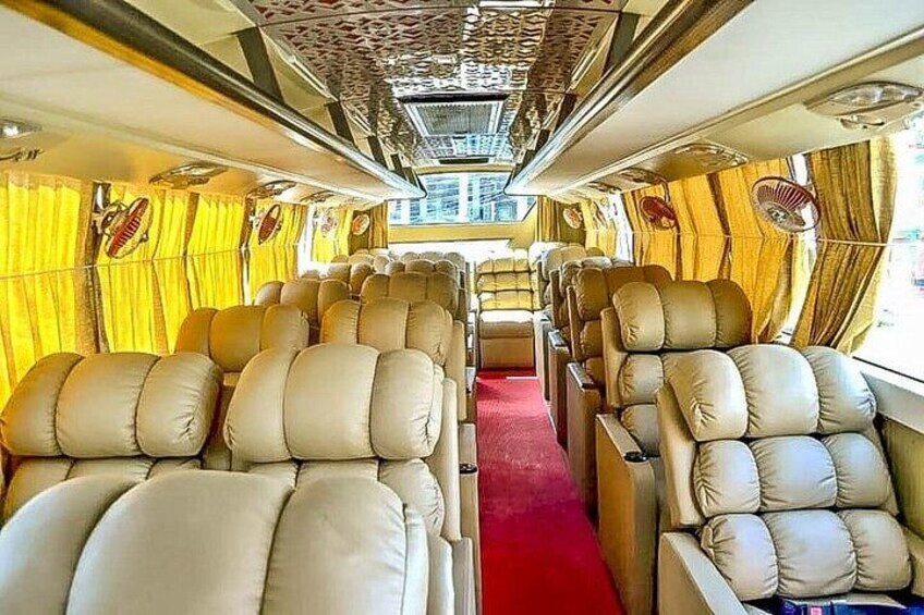 A train interior with rows of beige upholstered seats, yellow curtains, and a red carpet. 2