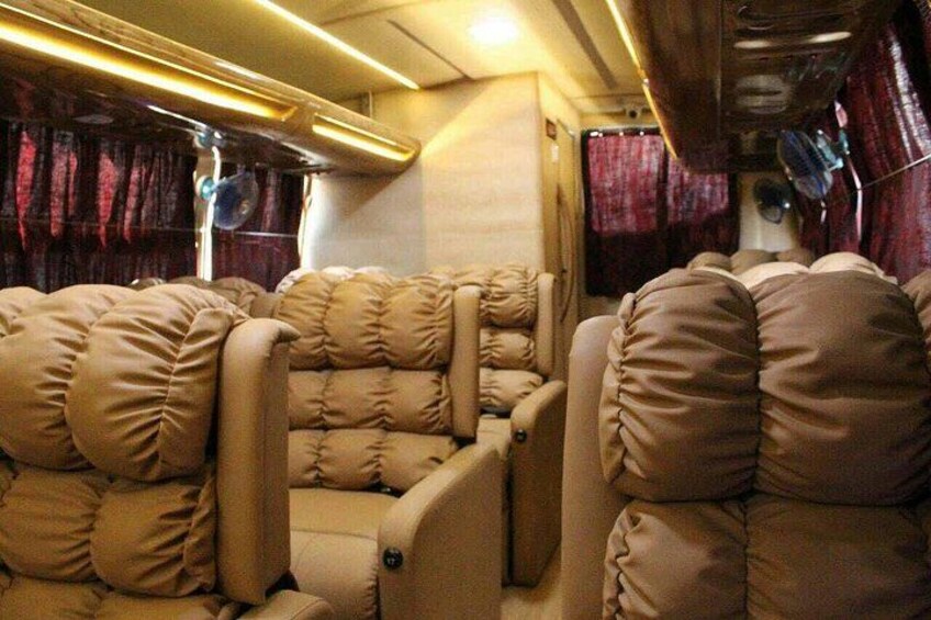 A train interior with beige upholstered seats and curtains. 5