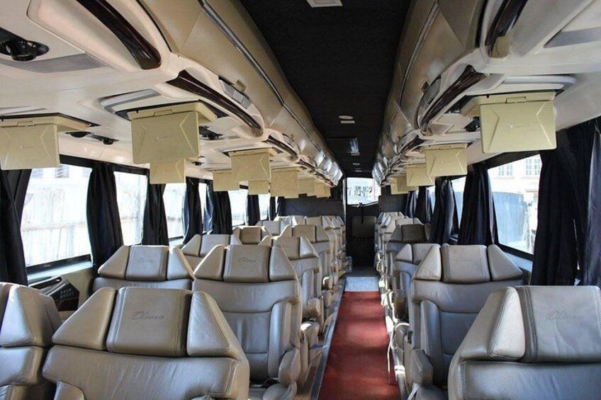 A train interior with rows of seats, overhead luggage compartments, and windows with curtains. 3