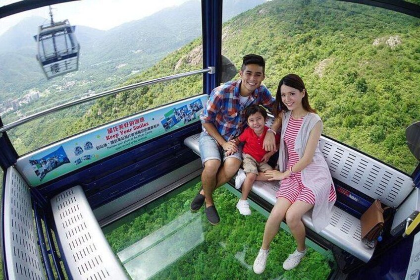 Una famiglia su una piattaforma panoramica con fondo in vetro che offre una vista mozzafiato su un paesaggio montuoso. 1
