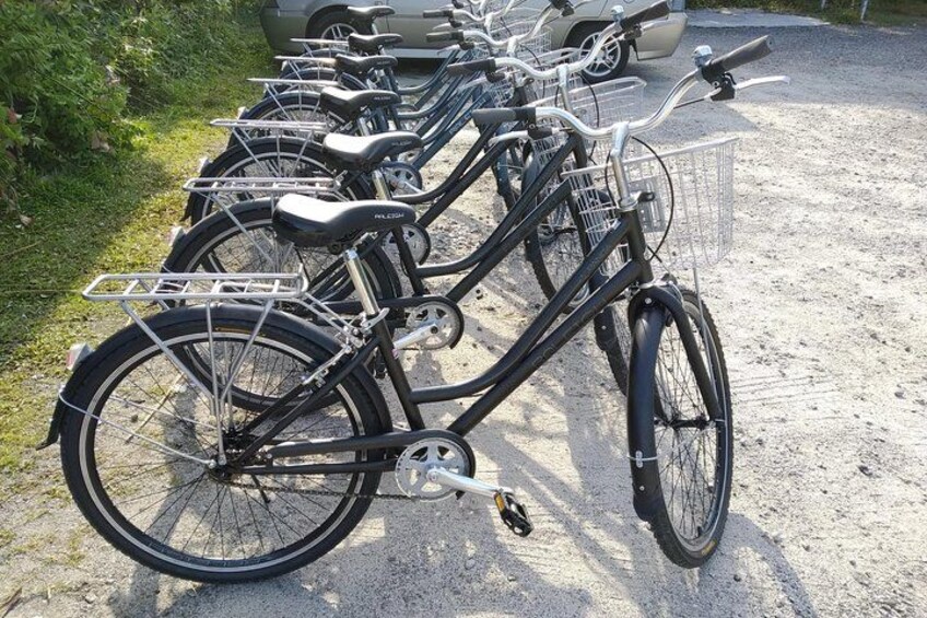 A row of bicycles parked on a gravel surface. 3