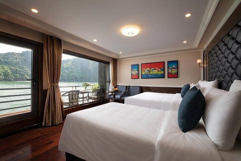 A hotel room with two beds, a large window with curtains, a view of a lake, and artwork on the wall. 1