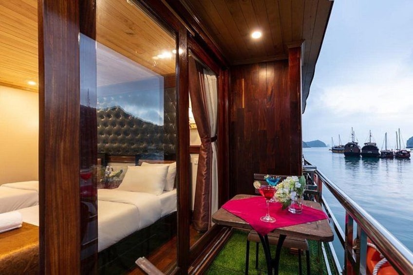 Terraza de madera con una mesa roja y un sofá blanco, con vistas a un puerto deportivo lleno de barcos. 1
