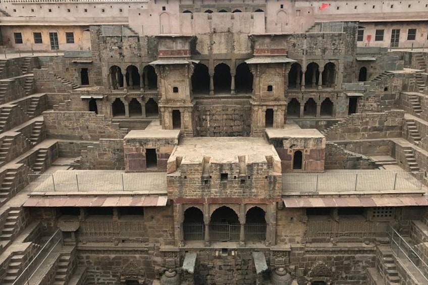 An ancient, multi-tiered stone structure with arched passageways and a central courtyard. 2