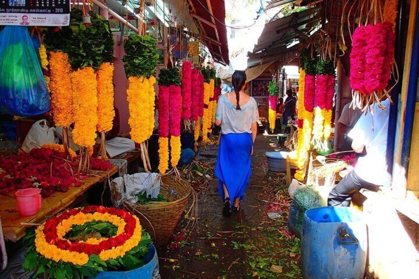A market with colorful flower arrangements and a person walking through. 3