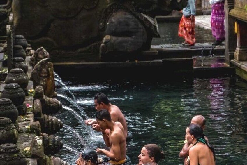 People bathing in a water body with stone sculptures and steps. 4
