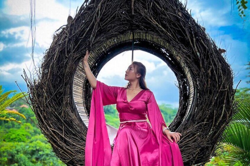 A person in a pink dress standing inside a circular woven structure. 2
